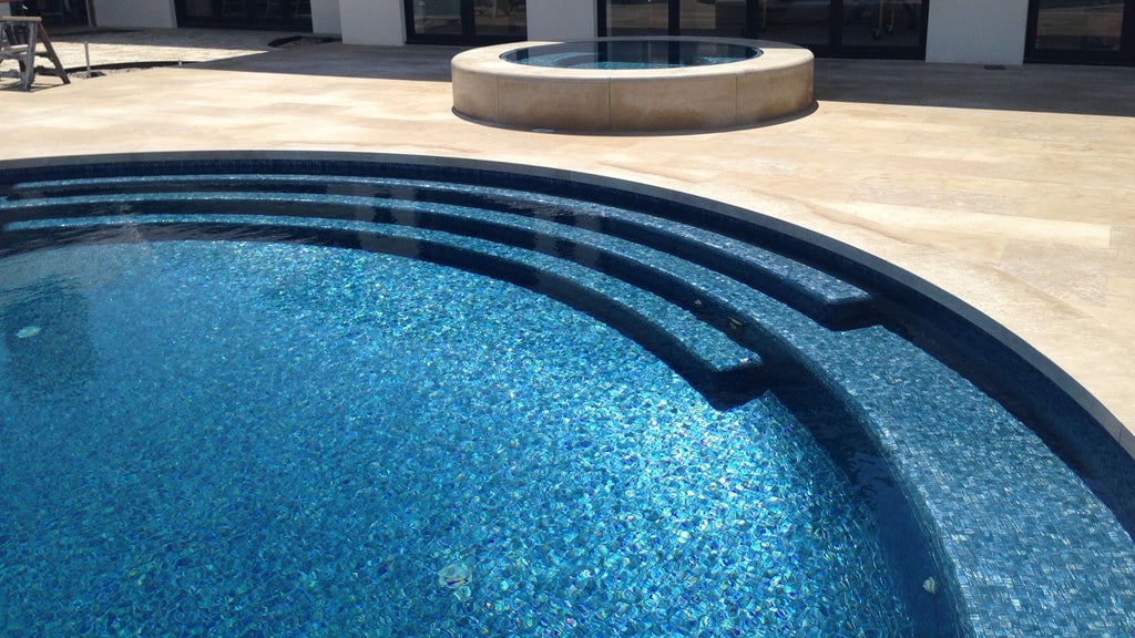 A luxury pool in the backyard of a modern home. It's tiled completely in the Blue Moon 1