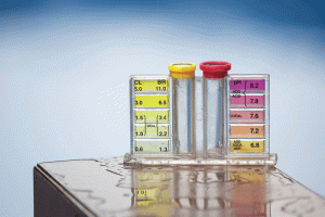 A close-up of a pool water testing kit with two vials and color-coded pH, chlorine, and bromine levels displayed for accurate water balance testing.